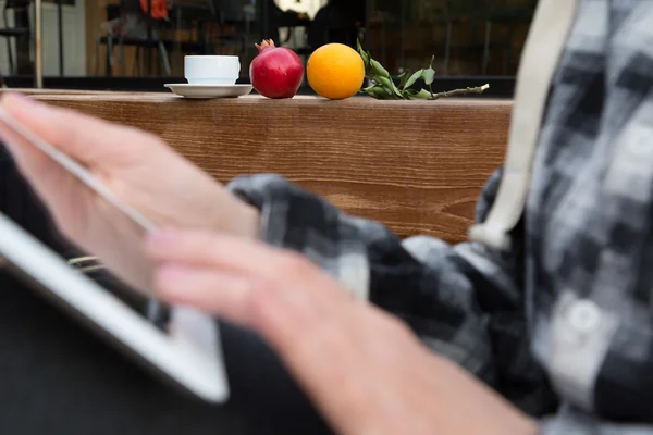 Rukou osoby procházení počítače tablet Pc obrazovky hrnek na kávu a ovoce — Stock fotografie