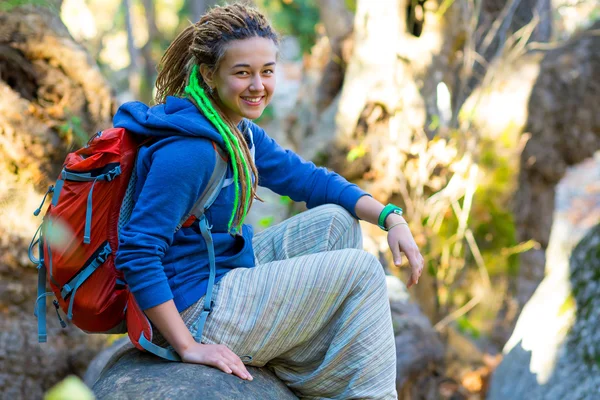 Linda chica sentada en el tallo caído del árbol en el bosque salvaje —  Fotos de Stock