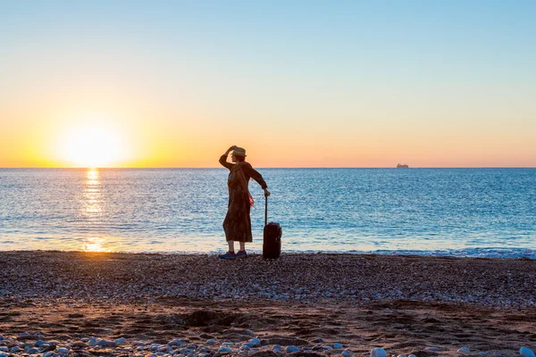 Reisende Frau bleibt bei Sonnenaufgang am Strand — Stockfoto
