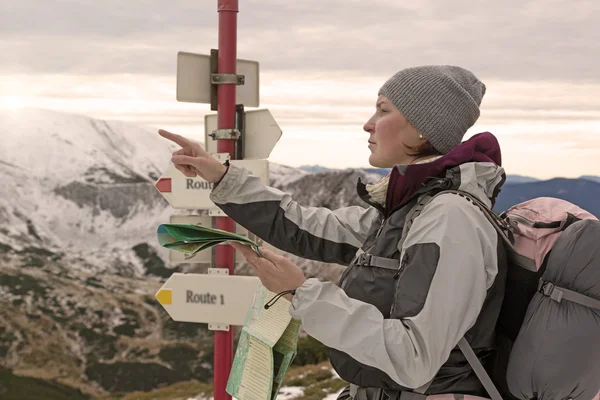 Турист, останавливающийся в Trail Sign и смотрящий на карту — стоковое фото