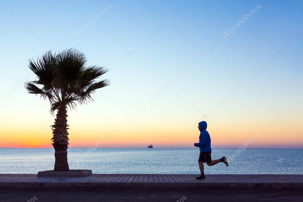 Young Man jogging on Seafront making Morning Fitness