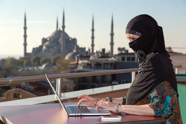 Παραδοσιακα ντυμενες μουσουλμανική γυναίκα που εργάζεται στον υπολογιστή — Φωτογραφία Αρχείου