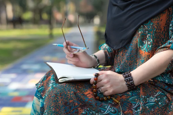 Studente arabo seduto nel Parco Universitario e fare appunti a mano — Foto Stock