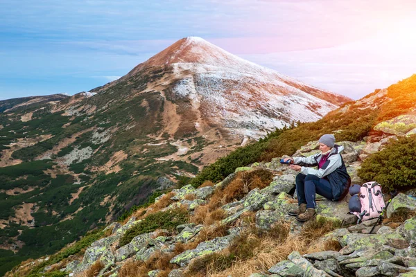 Female Hiker sitting on green Stone and using Thermos — Stok fotoğraf