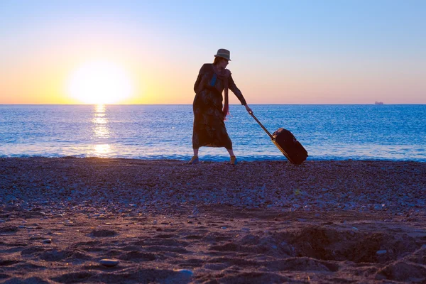Silueta de dama caminando por el mar Surf tirando de maleta de viaje —  Fotos de Stock