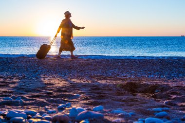 Deniz seyahat bavul çekerek Surf yürüyen kadın silüeti