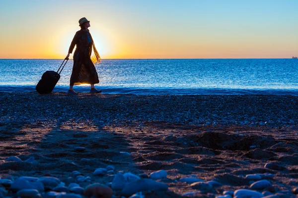 Silueta de dama caminando por el mar Surf tirando de maleta de viaje — Foto de Stock