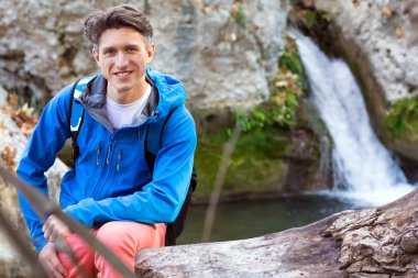 Yakışıklı erkek Hiker ağaç hendek gölde oturan portresi