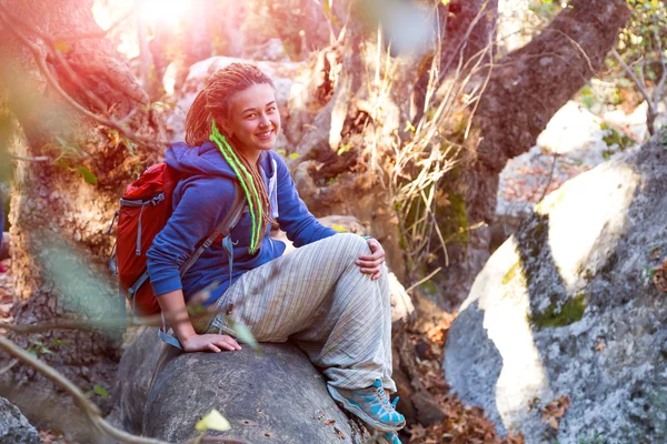 Söt flicka sitter på fallna träd stjälk i vilda skogen — Stockfoto