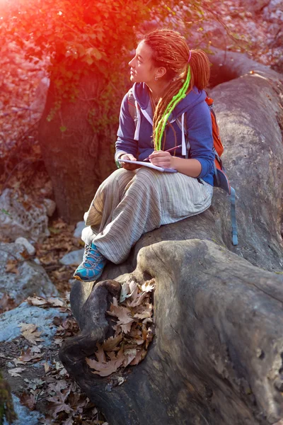 Menina bonito sentado na floresta e desenho esboço em seu livro de notas — Fotografia de Stock