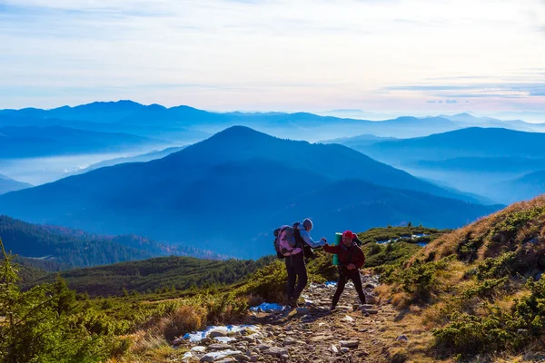 Два туристів, допомагаючи один одному на слід гори — стокове фото