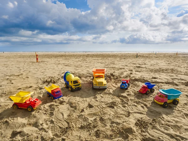 Groep van speelgoed werken trucks van verschillende grootten en kleuren die zijn gerangschikt in een halve cirkel op het strand — Stockfoto