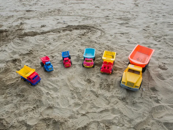 Group of toy working trucks on a sandy beach — Stock Photo, Image