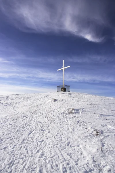 Croix blanche au sommet d'une montagne enneigée — Photo
