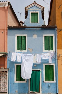 sky blue little house in Burano with white sheets and clothes ha clipart