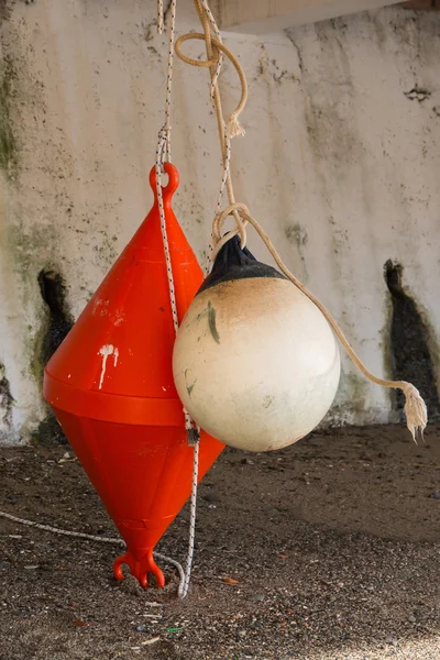 Orange conical buoy and white spherical buoy hanging outside wat — Stock Photo, Image