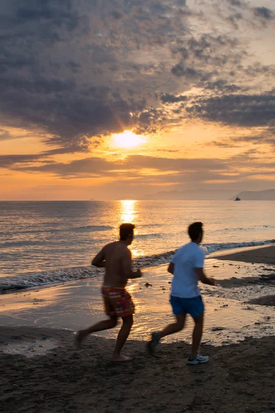 Двоє хлопців біжать на пляжі на заході сонця — стокове фото