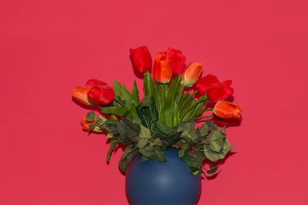 Strauß roter künstlicher Tulpen in einer blauen Vase — Stockfoto