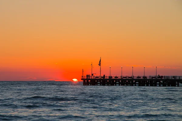 O cais do Forte dei Marmi ao pôr-do-sol, as pessoas a ver o sol — Fotografia de Stock