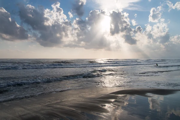 Raios de sol filtrar através das nuvens em mar áspero e praia — Fotografia de Stock