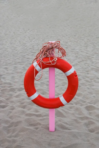 Lifebuoy with a long rope hung on a pink stake — Stock Photo, Image