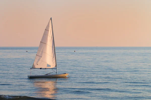 Small sailboat in the water next to the beach — Stock Photo, Image