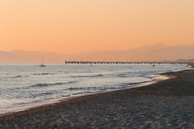 Forte dei Marmi'nın iskelesi yanındaki günbatımında yelken yelkenli 