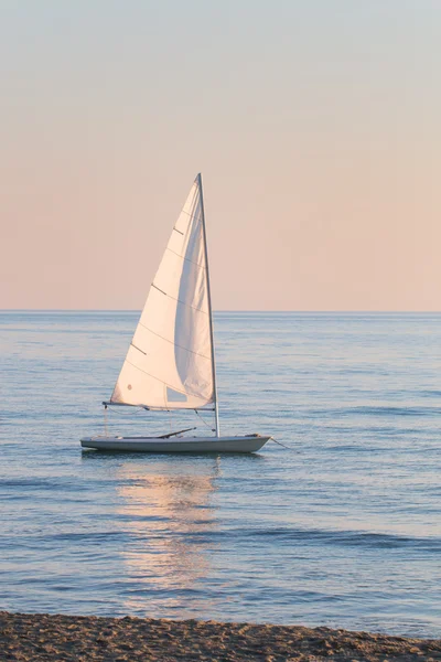 Small sailboat in the water anchored next to the beach — Stock Photo, Image