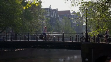 Amsterdam, geleneksel kanal sistemi ve Hollandalı bisikletçi tarafından kullanılan birçok köprü ile