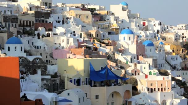 Ciudad de Oia con gente disfrutando de una bebida Santorini, Grecia — Vídeo de stock