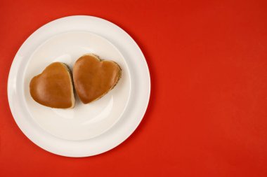 Beyaz bir tabakta iki kalp şeklinde hamburger. Yukarıdan manzara. Sevgililer Günü için yemek. Metnin için yer.