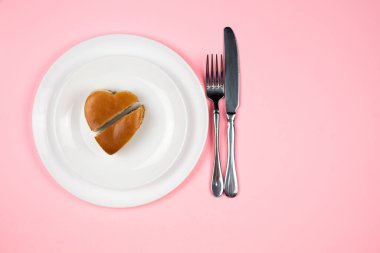 Beyaz bir tabakta kalp şeklinde bir Burger. Pembe stüdyo arka planı. Yukarıdan manzara. Sevgililer Günü Konsepti