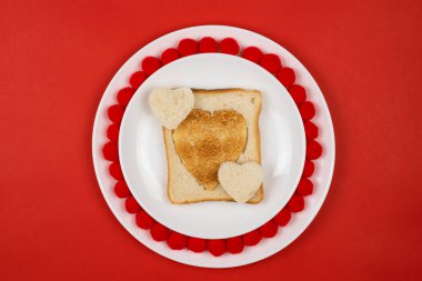 Beyaz seramik tabakta kızarmış çavdar ekmeği diliminde kalp şeklinde tost. Sevgililer Günü konsepti. Kahvaltı tasarımına bayıldım. Ev yapımı sağlıklı sandviç. Şenlikli öğle yemeği ya da kahvaltı. Boşluğu kopyala.