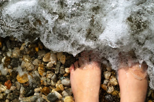 Woman's barefoot legs in a warm sea — Stock Photo, Image