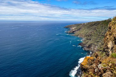Mavi deniz, sahilin yeşil ve kahverengileriyle, siyah kumlu plajlarıyla çelişiyor.