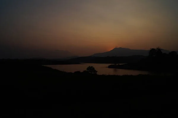 Sunset in dark backgroud behind the hill in karapuzha dam, Wayanad, Kerala, India. It is one of the largest earth dam in Kerala.