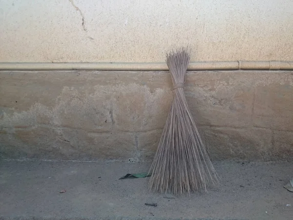Coconut Leaf Grass Broom at the wall .