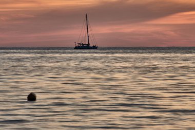 Küba. Trinidad. Günbatımının mor ışıltısında yelkenli bir tekne