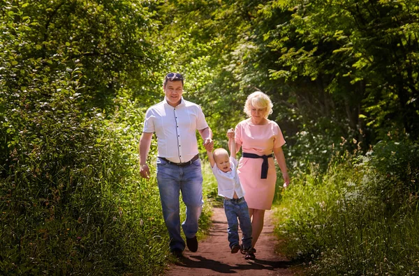 Fun walk of family in summer forest. Mother, father, boy walking in the park on a sunny day