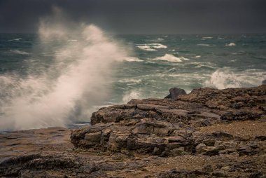 Dalgalar İngiltere 'nin Dorest kentindeki Portland Bill' in engebeli sahil şeridine çarpıyor.