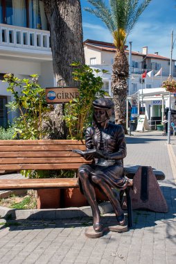 Kuzey Kıbrıs, Kyrenia 'da bir bankta oturmuş kitap okuyan bir kızın heykeli.