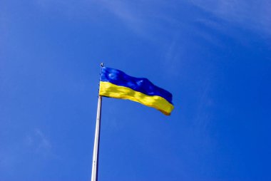 Ukrayna bayrağı açık mavi gökyüzünde dalgalanıyor.