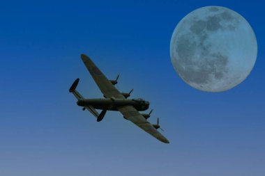 Bir Avro Lancaster II. Dünya Savaşı dönemi ağır bombardıman uçağı dolunay ışığında uçuyor.