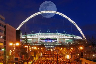 Londra, İngiltere 'deki Wembley Stadyumu' nun parlak kemerinin arkasında dolunay var.