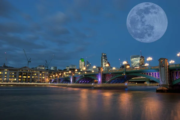 英国ロンドンのテムズ川南岸からサウスワーク橋を渡る満月 — ストック写真