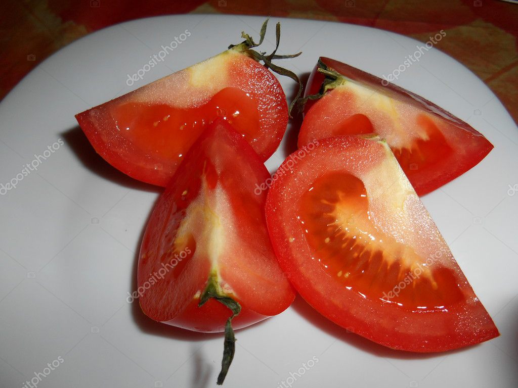 Tomato cut in four quarters on white plate — Stock Photo © ValEs1989