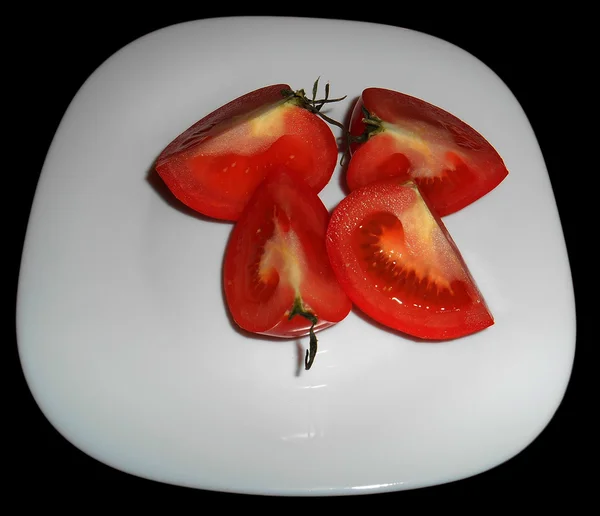 Tomato cut in four quarters on white plate — Stock Photo © ValEs1989 60170983