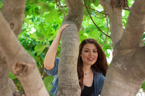 Girl smiling behind a fig tree — Stock Photo, Image