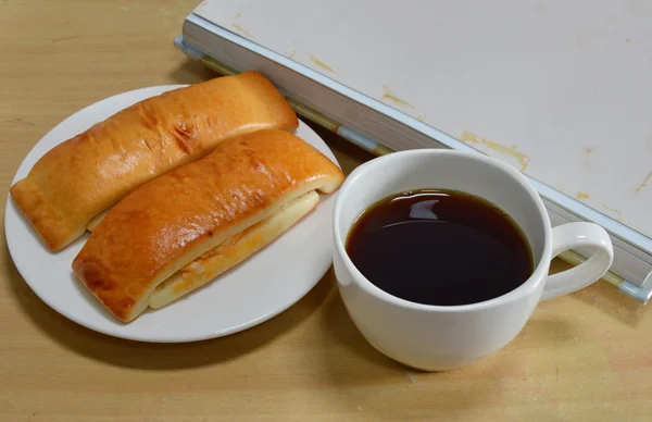 Bröd stick och svart kaffe på skrivbord — Stockfoto