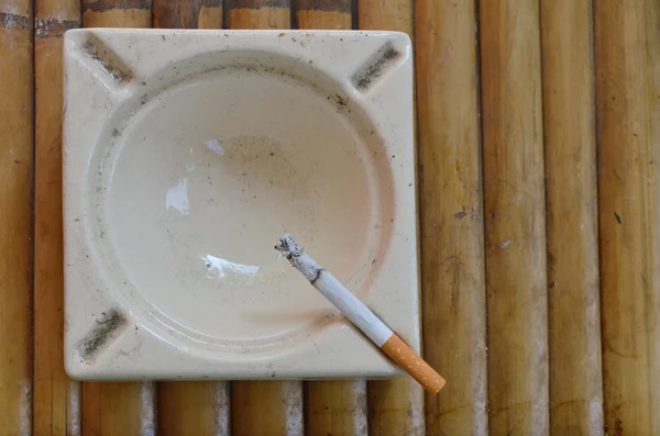 Cigarette in tile ashtray on bamboo — Stock Photo, Image